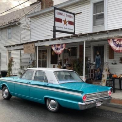 Photo of the front of Simple Tymes showing an antique car, and the front porch area