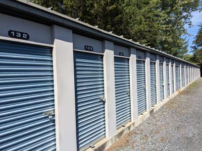 Exterior view of a self storage facility with blue doors, located against a backdrop of clear blue skies